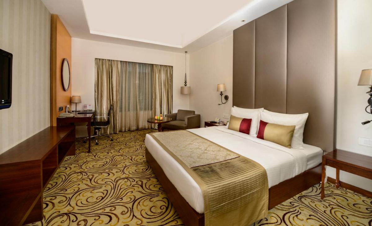 a hotel room with a large bed and a desk at Pride Plaza Hotel, Kolkata in Kolkata