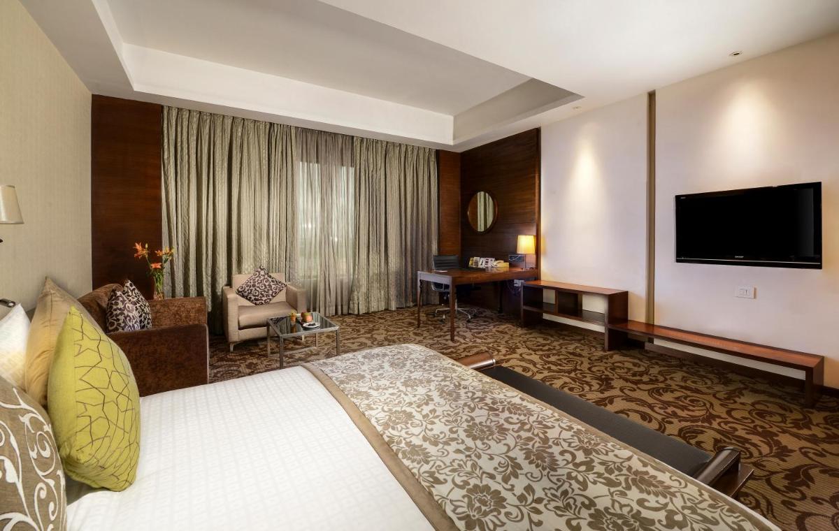 a hotel room with a bed and a flat screen tv at Pride Plaza Hotel, Kolkata in Kolkata