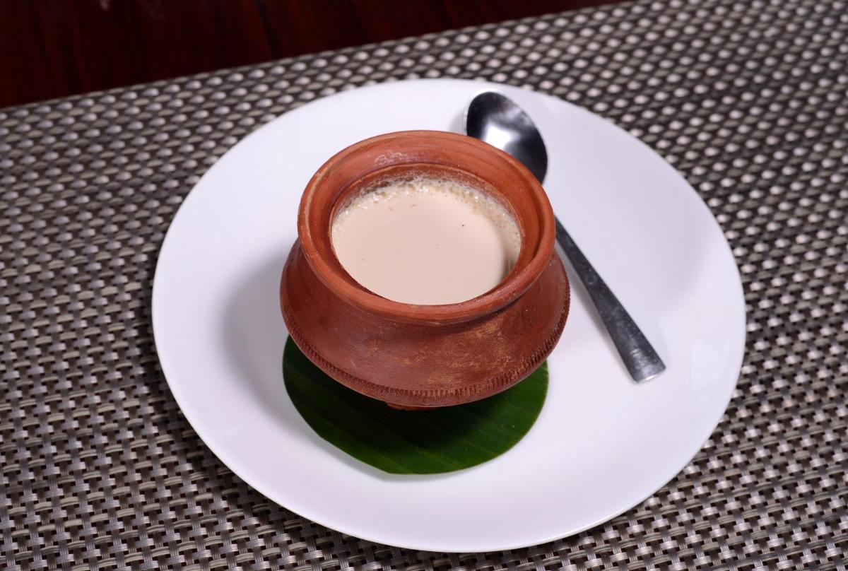 a cup of coffee on a plate with a spoon at Pride Plaza Hotel, Kolkata in Kolkata