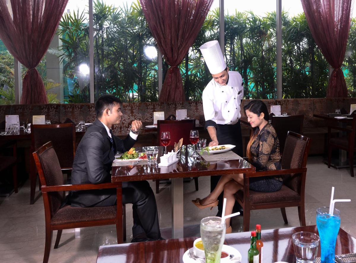 a man and woman sitting at a table with a chef at Pride Plaza Hotel, Kolkata in Kolkata