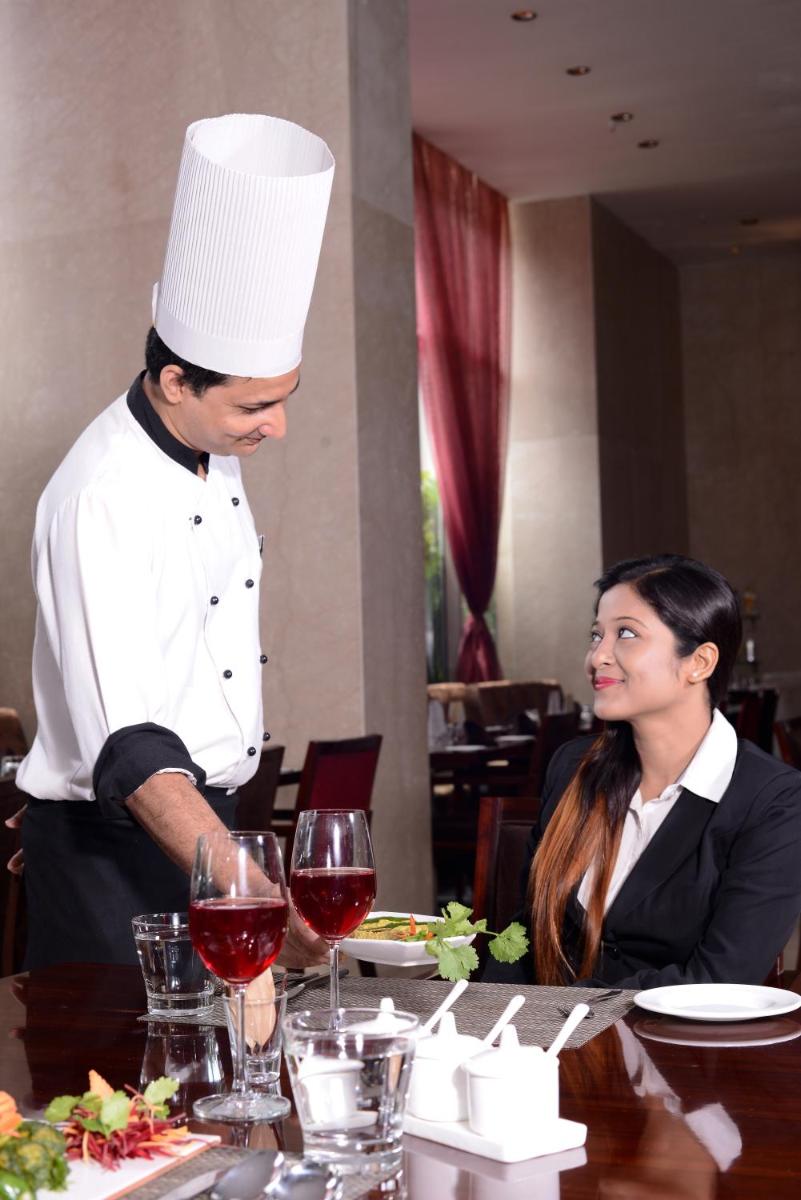 a man in a chef hat standing over a table with a woman at Pride Plaza Hotel, Kolkata in Kolkata