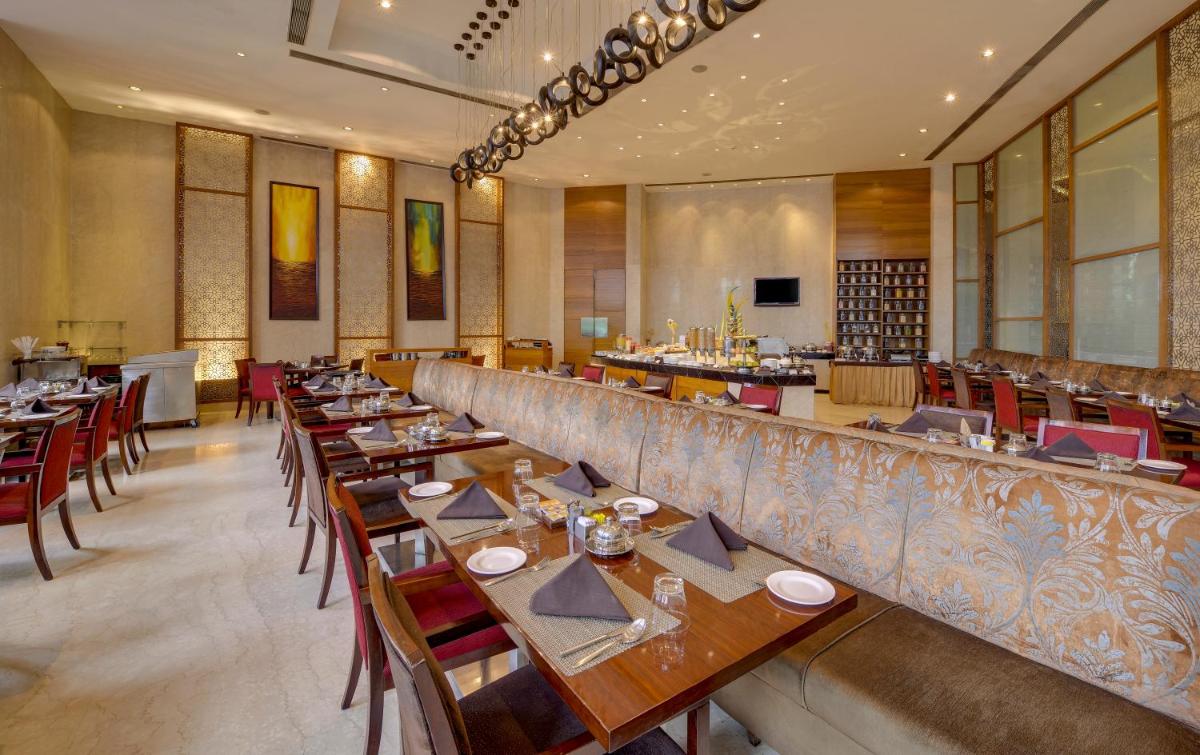a restaurant with a long bar with tables and chairs at Pride Plaza Hotel, Kolkata in Kolkata