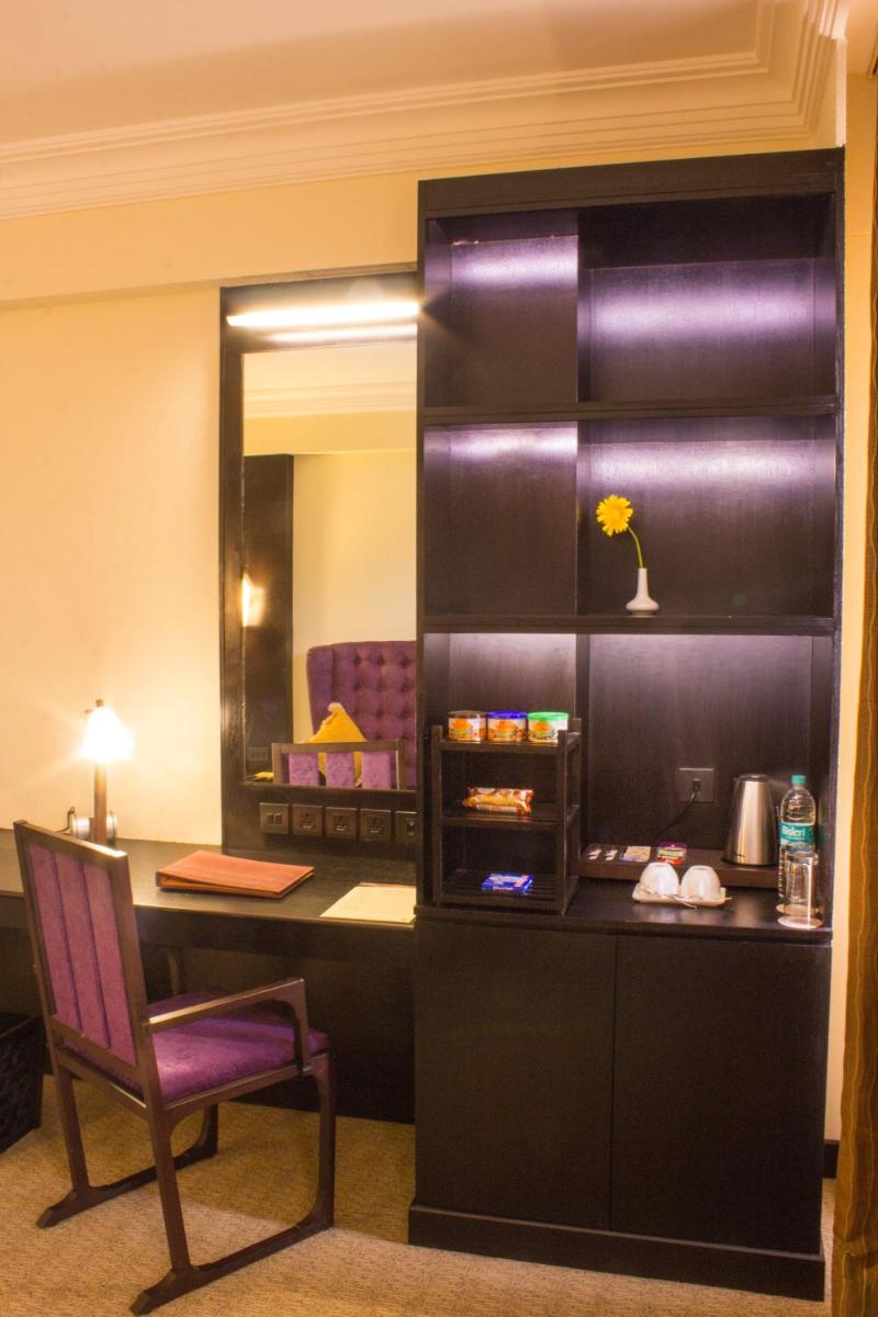 a room with a desk and a chair and a mirror at Sterlings Mac Hotel in Bengaluru