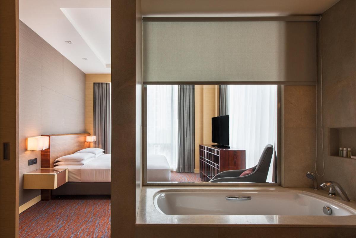 a hotel room with a tub and a bedroom at Hyatt Regency Lucknow Gomti Nagar in Lucknow