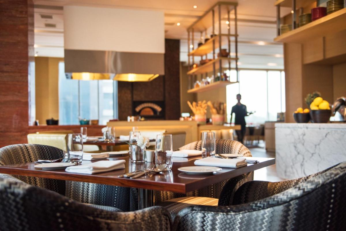 a restaurant with a wooden table and chairs at Hyatt Regency Lucknow Gomti Nagar in Lucknow