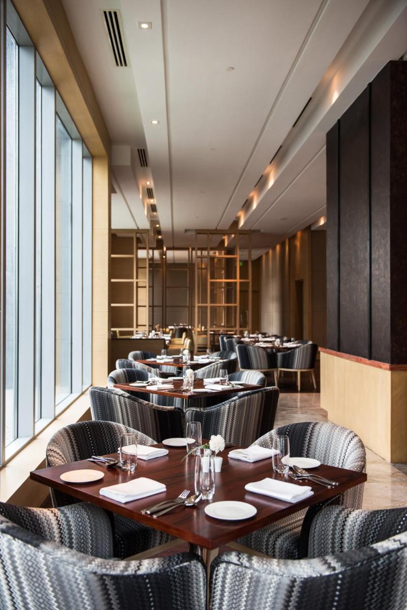 a dining room with tables and chairs and windows at Hyatt Regency Lucknow Gomti Nagar in Lucknow