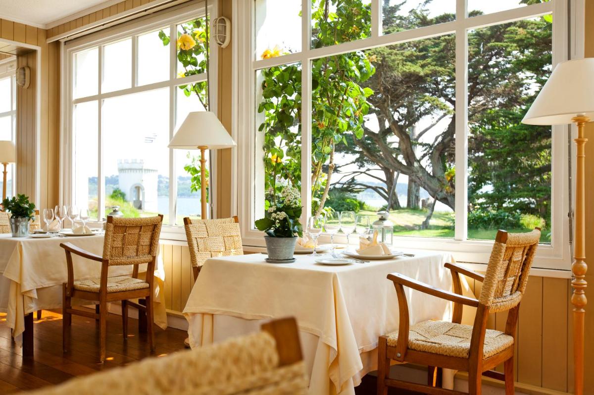 une salle à manger avec tables, chaises et fenêtres dans l'établissement Le Grand Hotel des Bains & Spa - Bretagne, à Locquirec