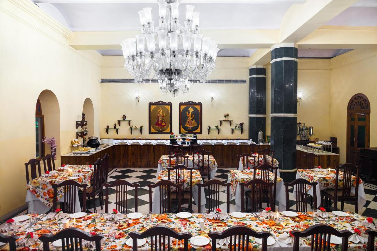 a dining room with tables and chairs and a chandelier at The Grand Imperial - Heritage Hotel in Agra