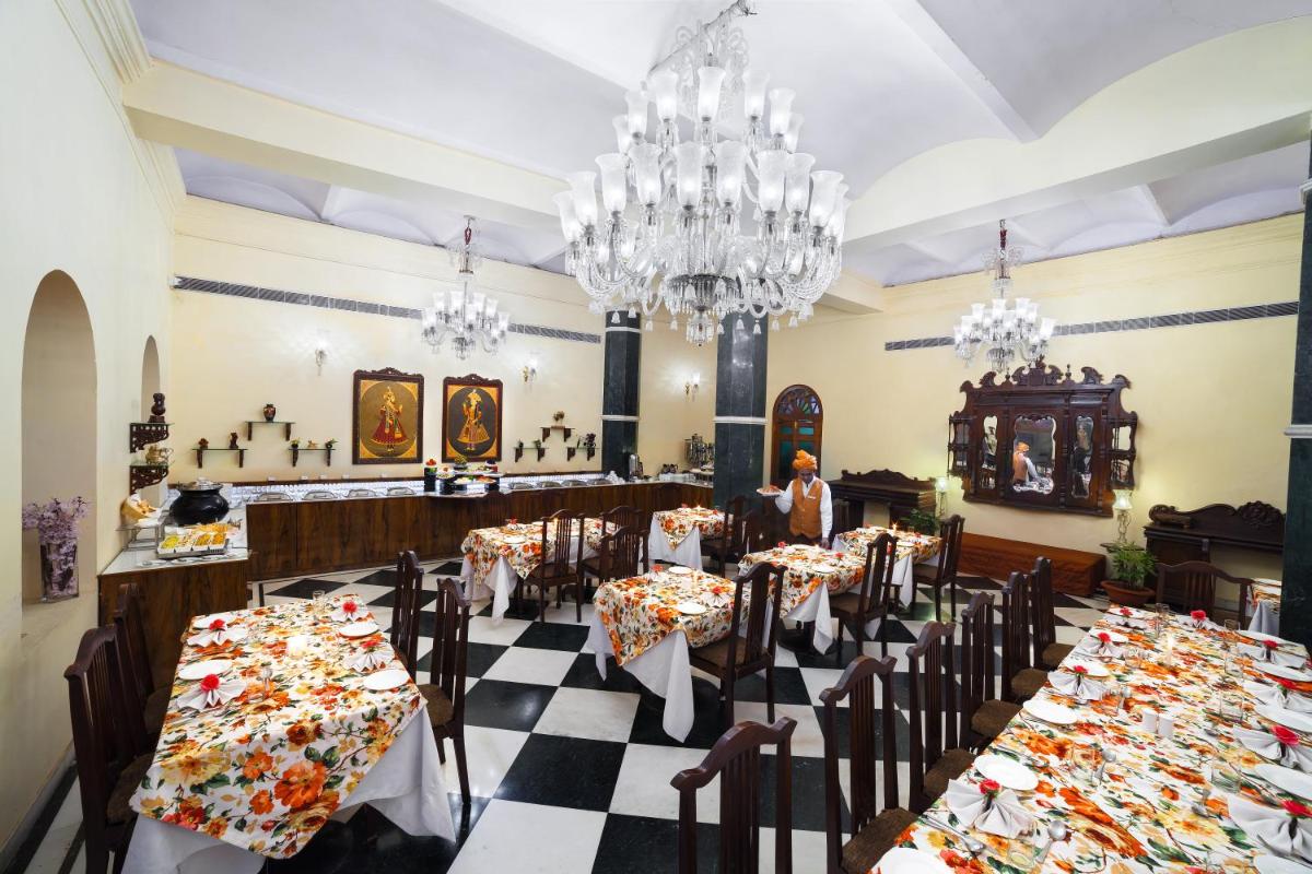 a restaurant with tables and chairs and chandeliers at The Grand Imperial - Heritage Hotel in Agra
