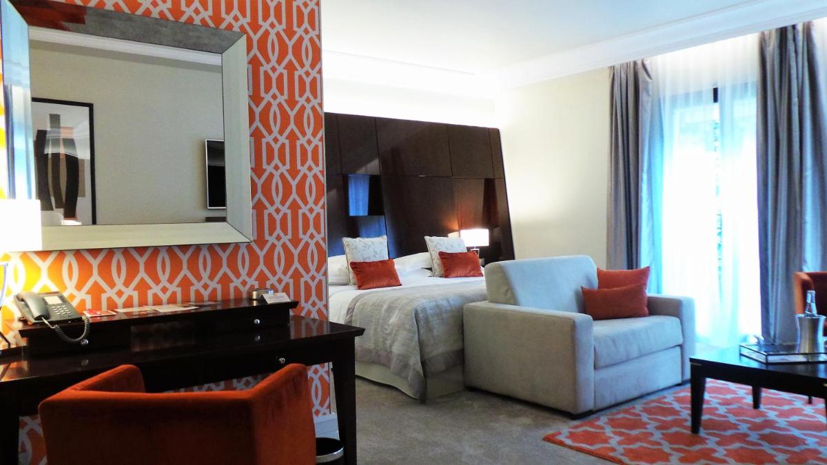 une chambre d'hôtel avec un lit, une chaise et un miroir dans l'établissement Hotel & Spa Le Pavillon, à Charbonnières-les-Bains 30 autres photos