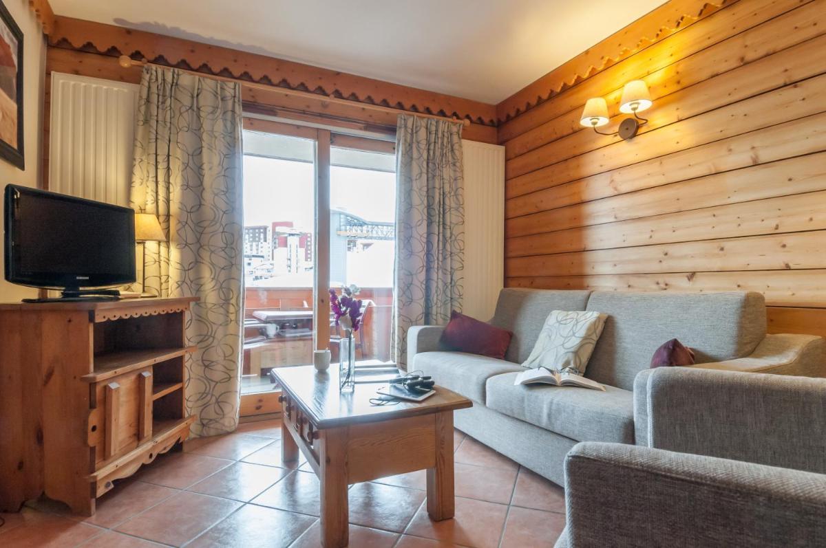 un salon avec un canapé et une télévision dans l'établissement Résidence Pierre & Vacances Premium Les Hauts Bois, à Aime La Plagne