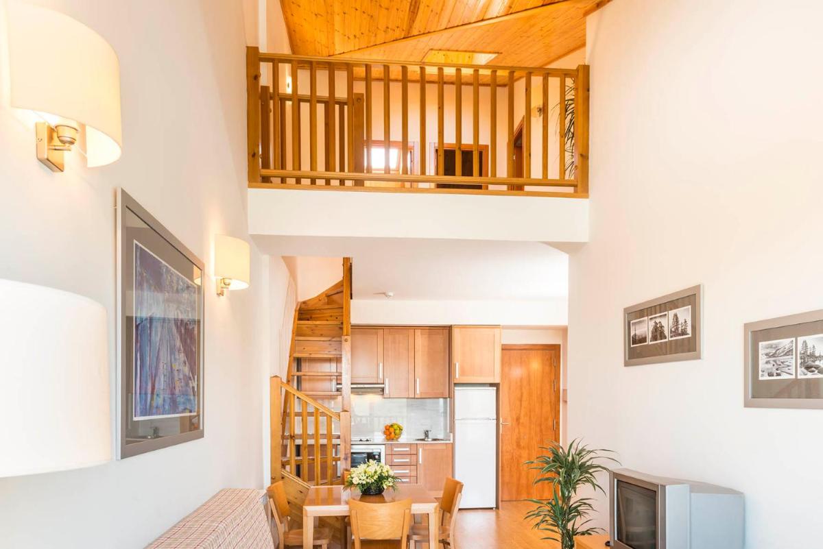 Una cocina y una sala de estar con mesa y sillas. en Guitart La Molina Aparthotel & Spa, en La Molina