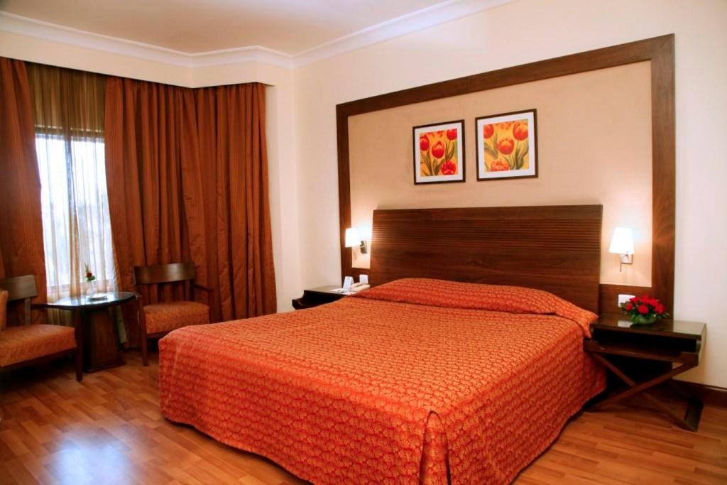 a hotel room with a bed with a orange bedspread at The Retreat Hotel & Convention Centre in Mumbai