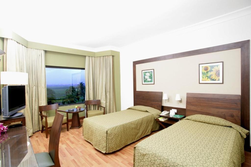 a hotel room with two beds and a television at The Retreat Hotel & Convention Centre in Mumbai
