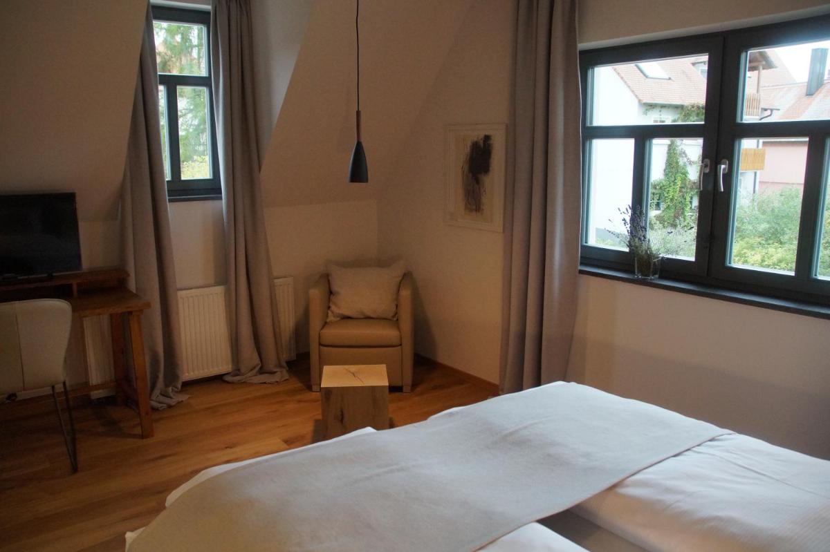 ein Schlafzimmer mit einem Bett und einem Stuhl und Fenstern in der Unterkunft Hotel Dorfmühle in Lehrberg