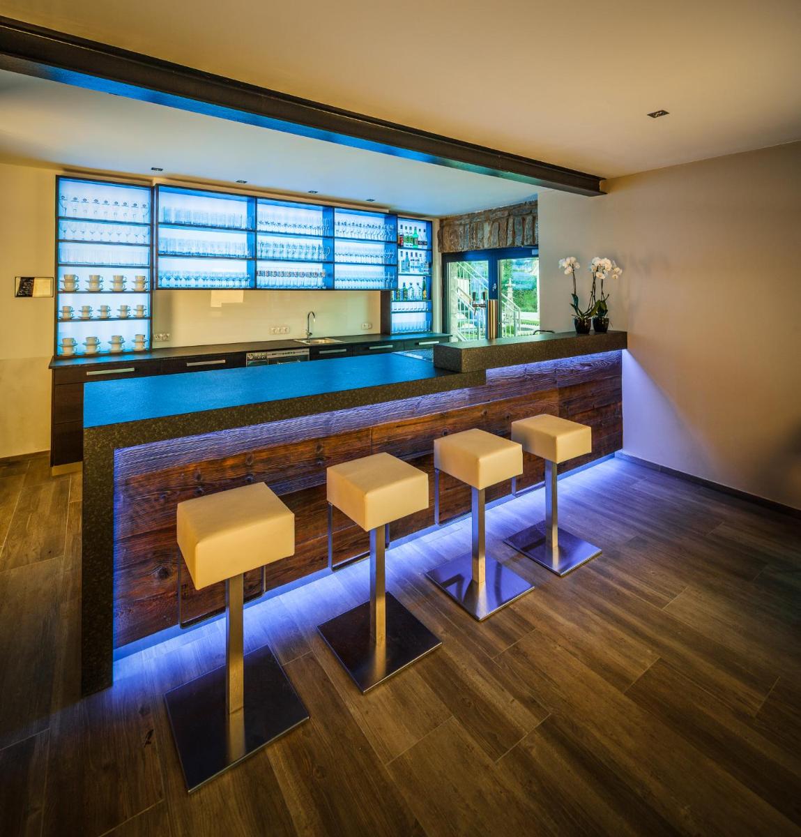 eine Küche mit einer Bar mit Hockern und einer Theke in der Unterkunft Hotel Dorfmühle in Lehrberg