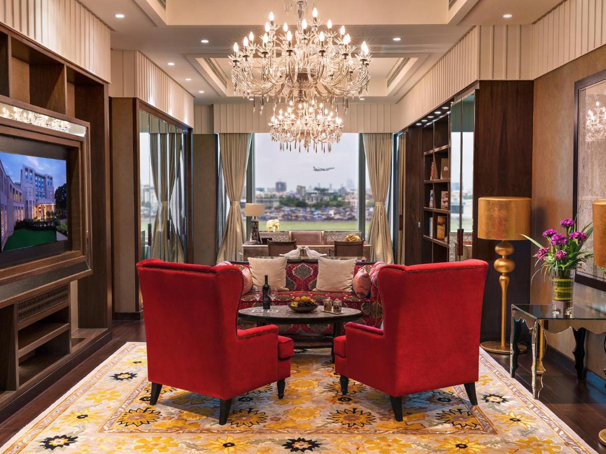 a living room with red chairs and a chandelier at Taj Santacruz in Mumbai