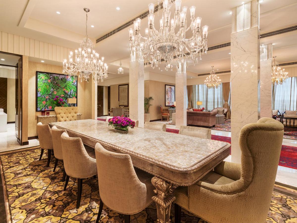 a dining room with a large table and chandeliers at Taj Santacruz in Mumbai