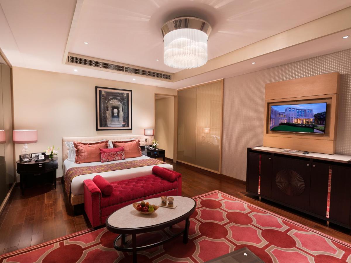 a hotel room with a bed and a red couch at Taj Santacruz in Mumbai