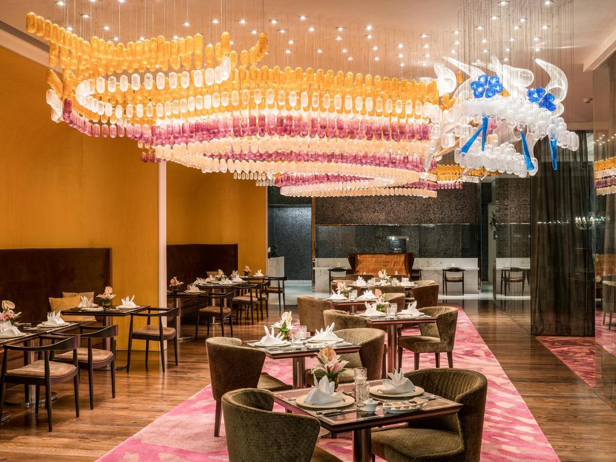 a dining room with tables and a chandelier at Taj Santacruz in Mumbai