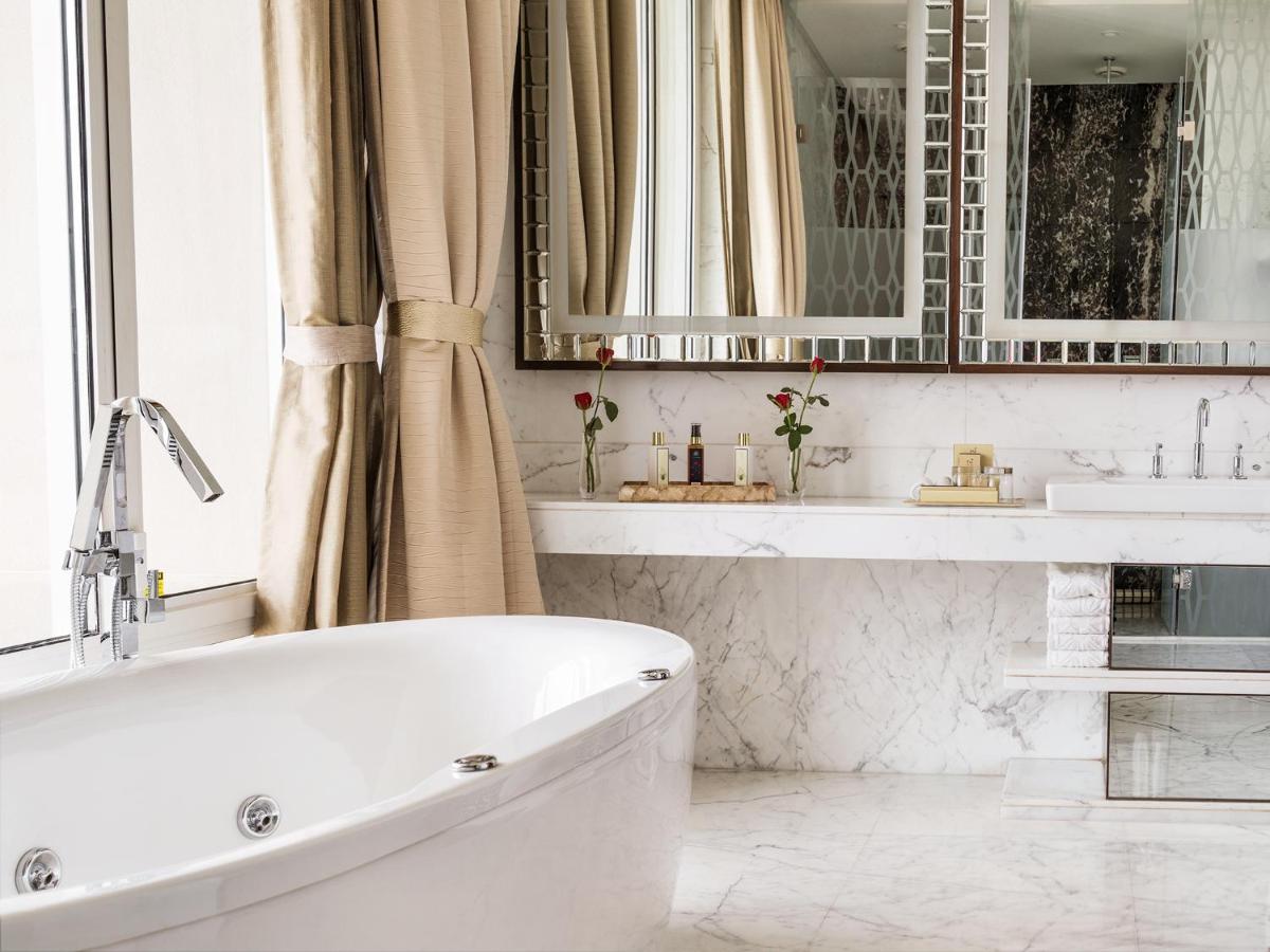 a white bathroom with two sinks and a tub at Taj Santacruz in Mumbai