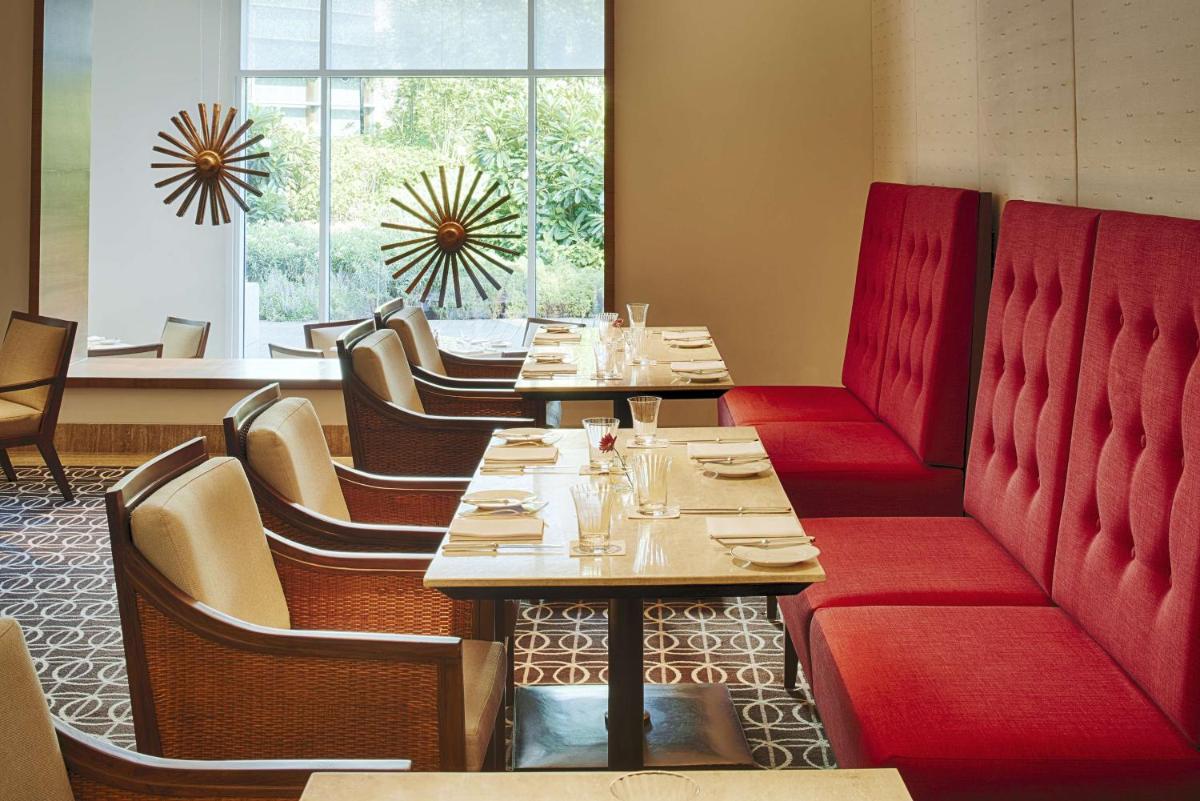 a dining room with tables and chairs with red booths at Park Hyatt Chennai in Chennai