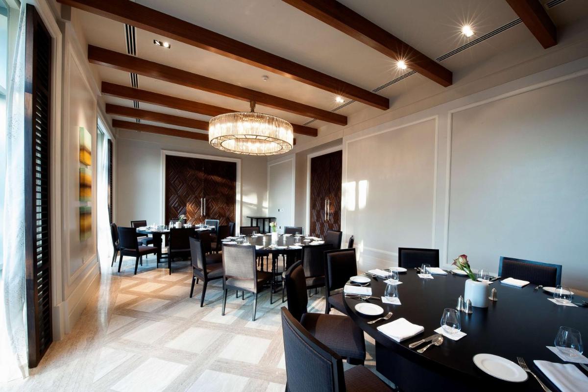 a dining room with tables and chairs and a chandelier at Park Hyatt Chennai in Chennai