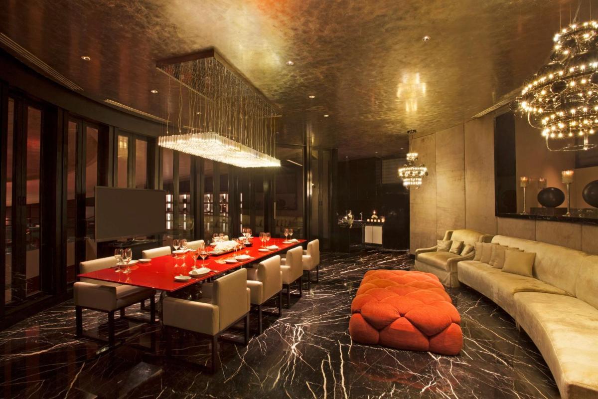 a dining room with a long table and a couch at Park Hyatt Chennai in Chennai