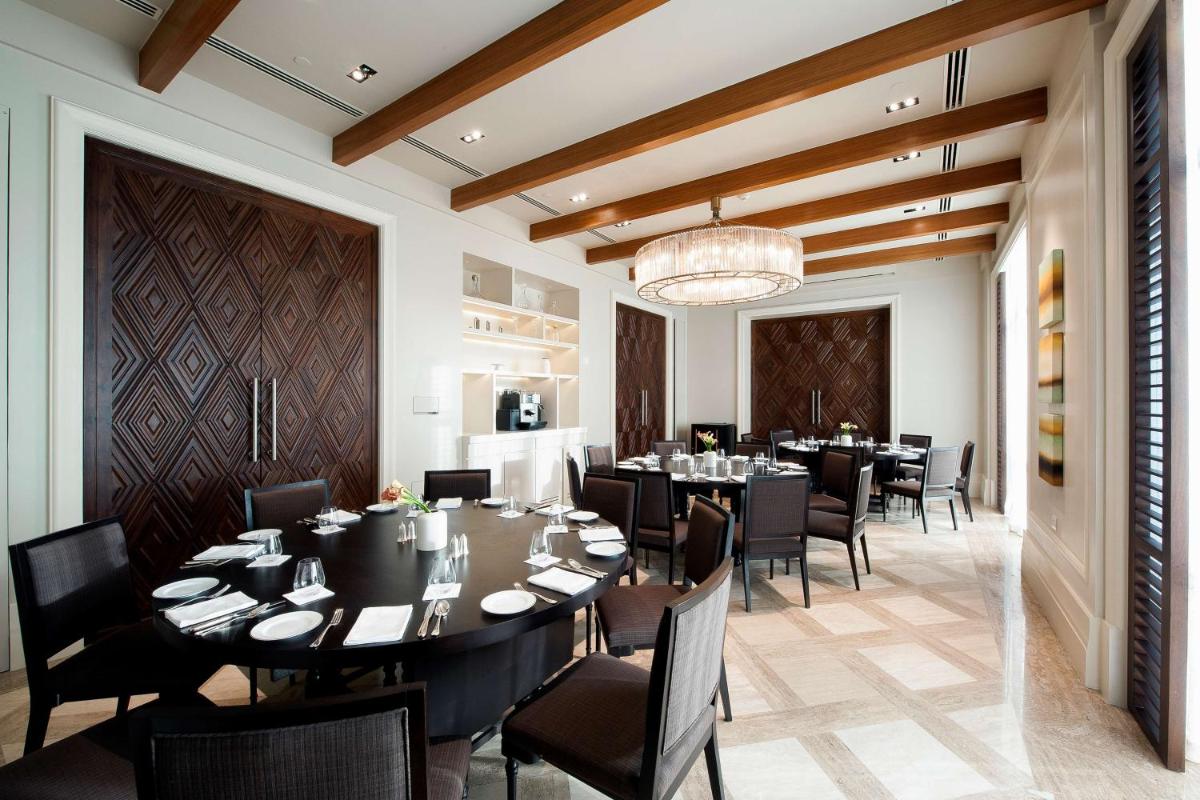a dining room with tables and chairs and a chandelier at Park Hyatt Chennai in Chennai