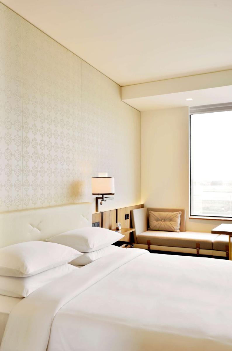 a hotel room with two beds and a couch at Andaz Delhi, by Hyatt in New Delhi a hotel room with two beds and a couch at Andaz Delhi, by Hyatt in New Delhi