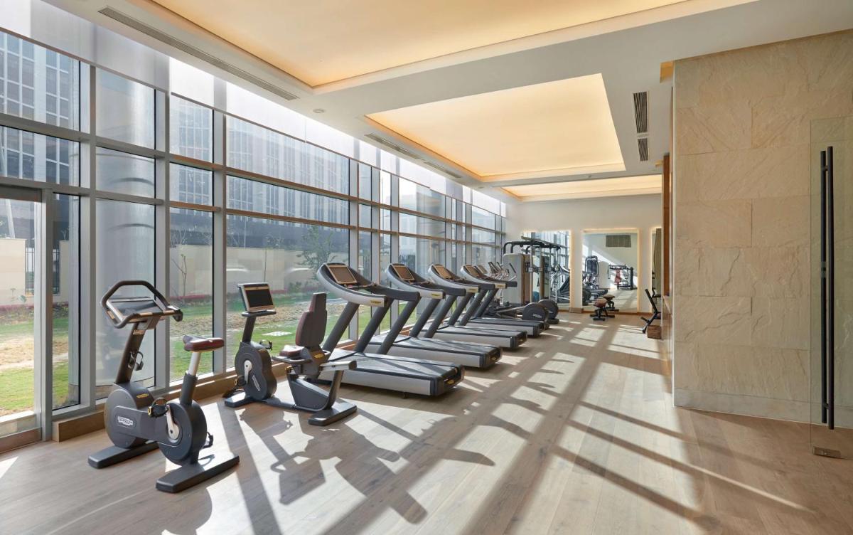 a gym with a row of treadmills and ellipticals at Andaz Delhi, by Hyatt in New Delhi a gym with a row of treadmills and ellipticals at Andaz Delhi, by Hyatt in New Delhi