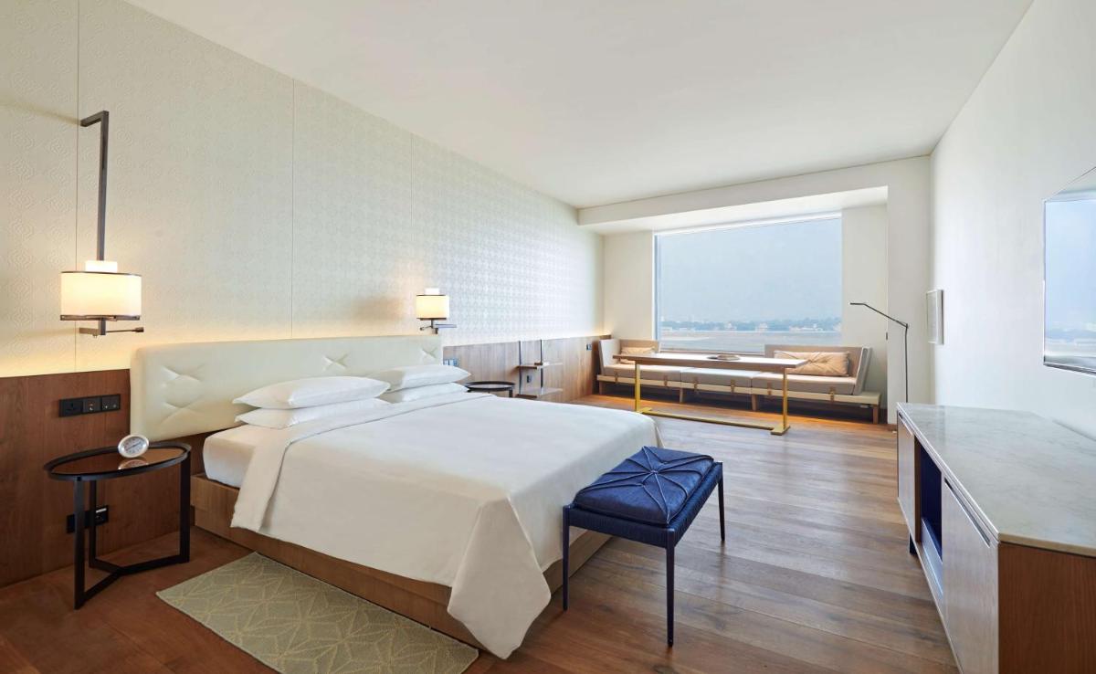 a bedroom with a large white bed and a couch at Andaz Delhi, by Hyatt in New Delhi a bedroom with a large white bed and a couch at Andaz Delhi, by Hyatt in New Delhi