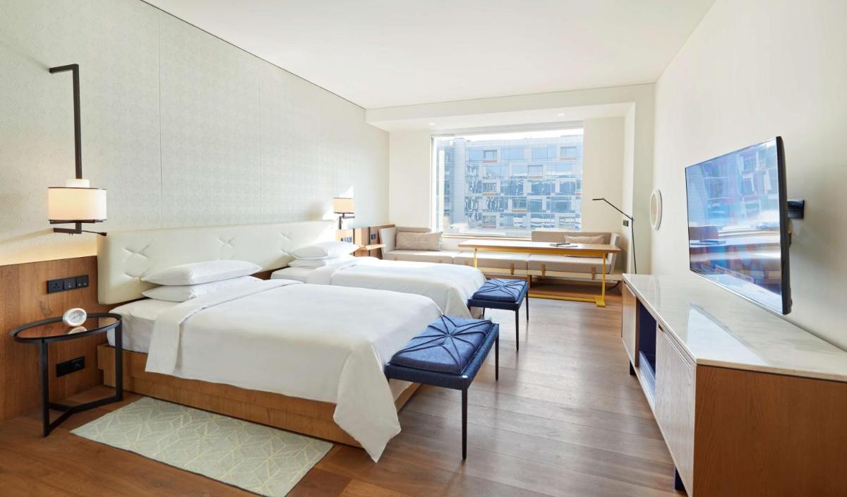 a hotel room with two beds and a television at Andaz Delhi, by Hyatt in New Delhi a hotel room with two beds and a television at Andaz Delhi, by Hyatt in New Delhi