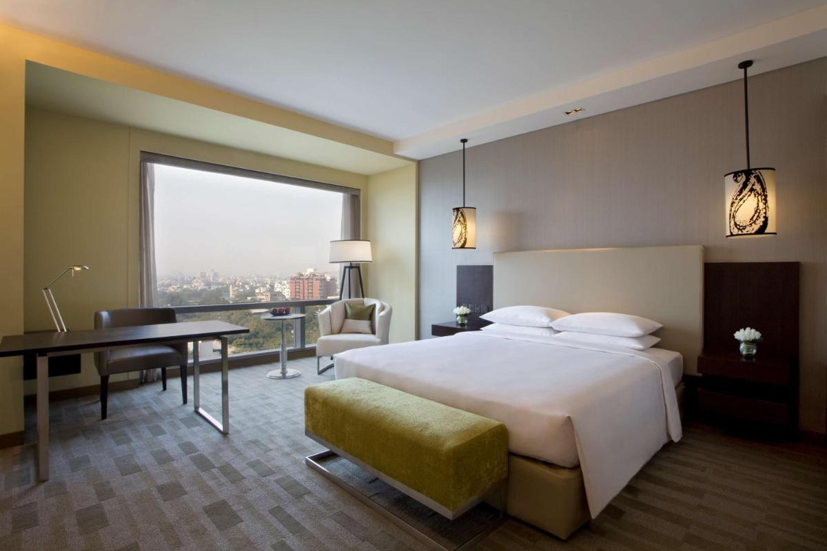 a hotel room with a bed and a desk and a window at Hyatt Regency Ahmedabad in Ahmedabad