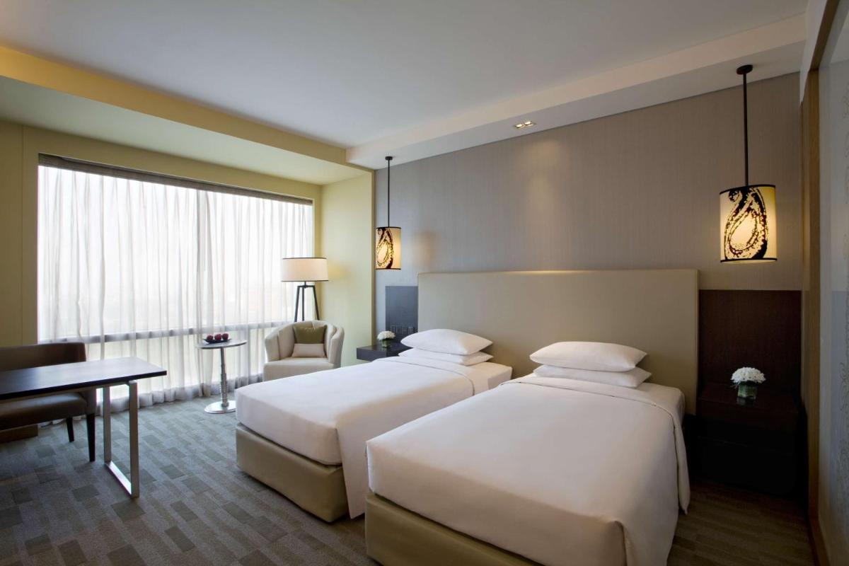 a hotel room with two beds and a desk at Hyatt Regency Ahmedabad in Ahmedabad