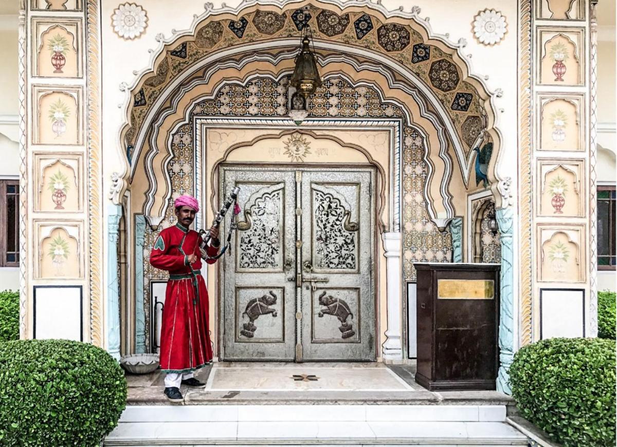 a woman in a red dress standing in front of a door at The Raj Palace (Small Luxury Hotels of the World) in Jaipur