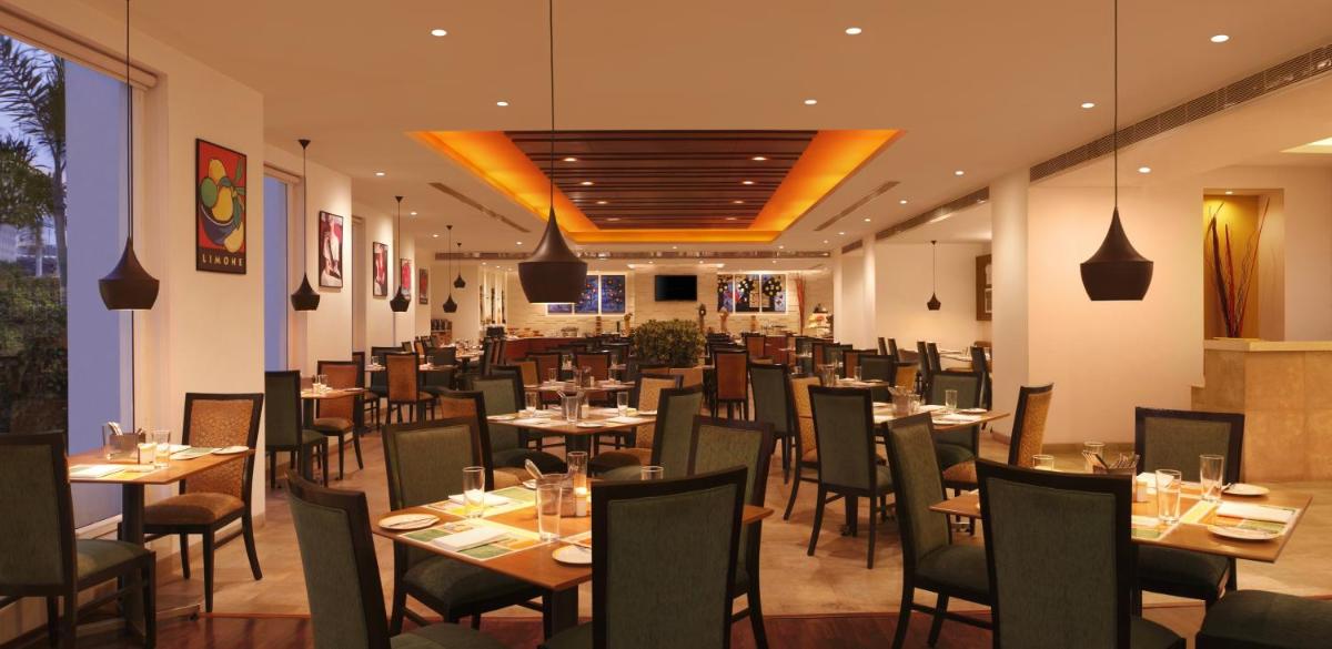 a restaurant with tables and chairs in a room at Lemon Tree Premier Hitec City Hyderabad in Hyderabad a restaurant with tables and chairs in a room at Lemon Tree Premier Hitec City Hyderabad in Hyderabad