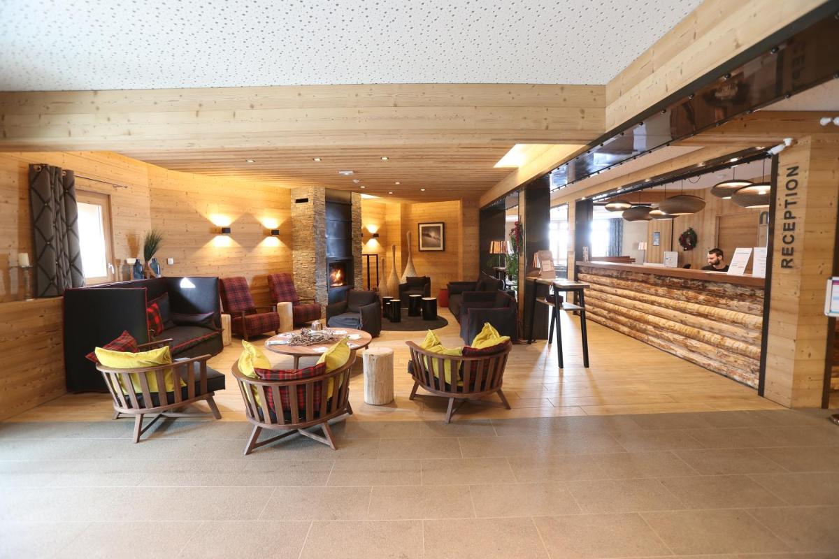 un hall d'hôtel avec des chaises et une table dans l'établissement Résidence Club MMV Le Cœur des Loges, aux Menuires