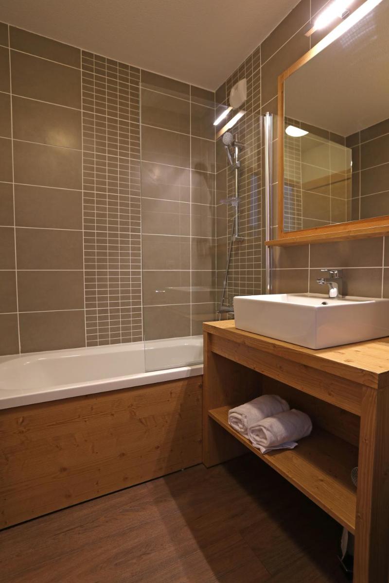 une salle de bains avec lavabo, baignoire et miroir dans l'établissement Résidence Club MMV Le Cœur des Loges, aux Menuires