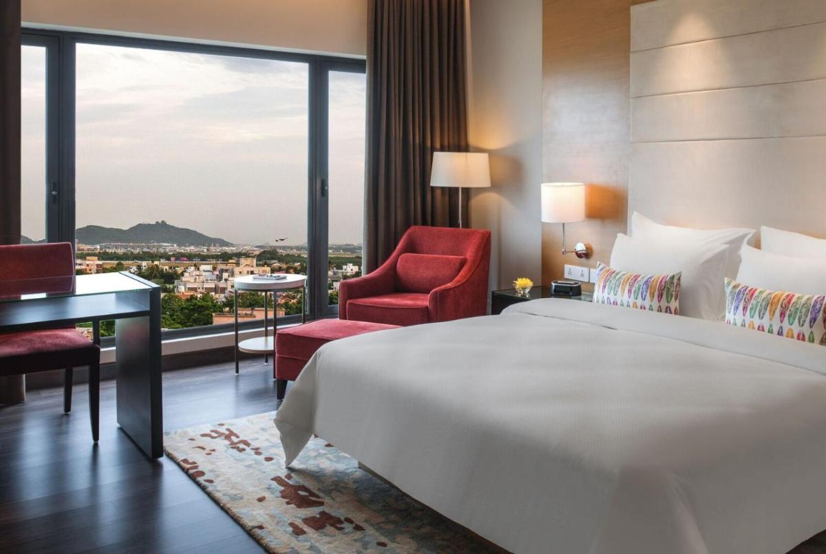 a hotel room with a large bed and a desk and chair at Feathers- A Radha Hotel, Chennai in Chennai