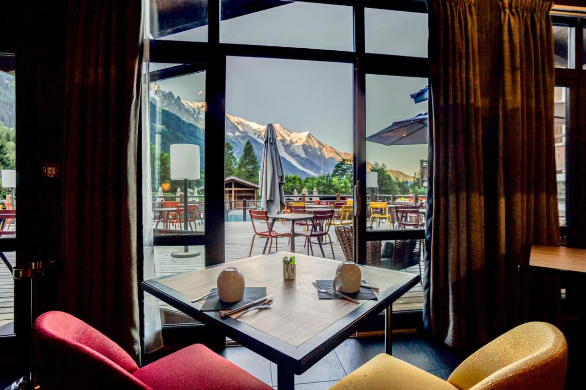 une pièce avec une table et des chaises et une grande fenêtre dans l'établissement Excelsior Chamonix Hôtel & Spa, à Chamonix-Mont-Blanc