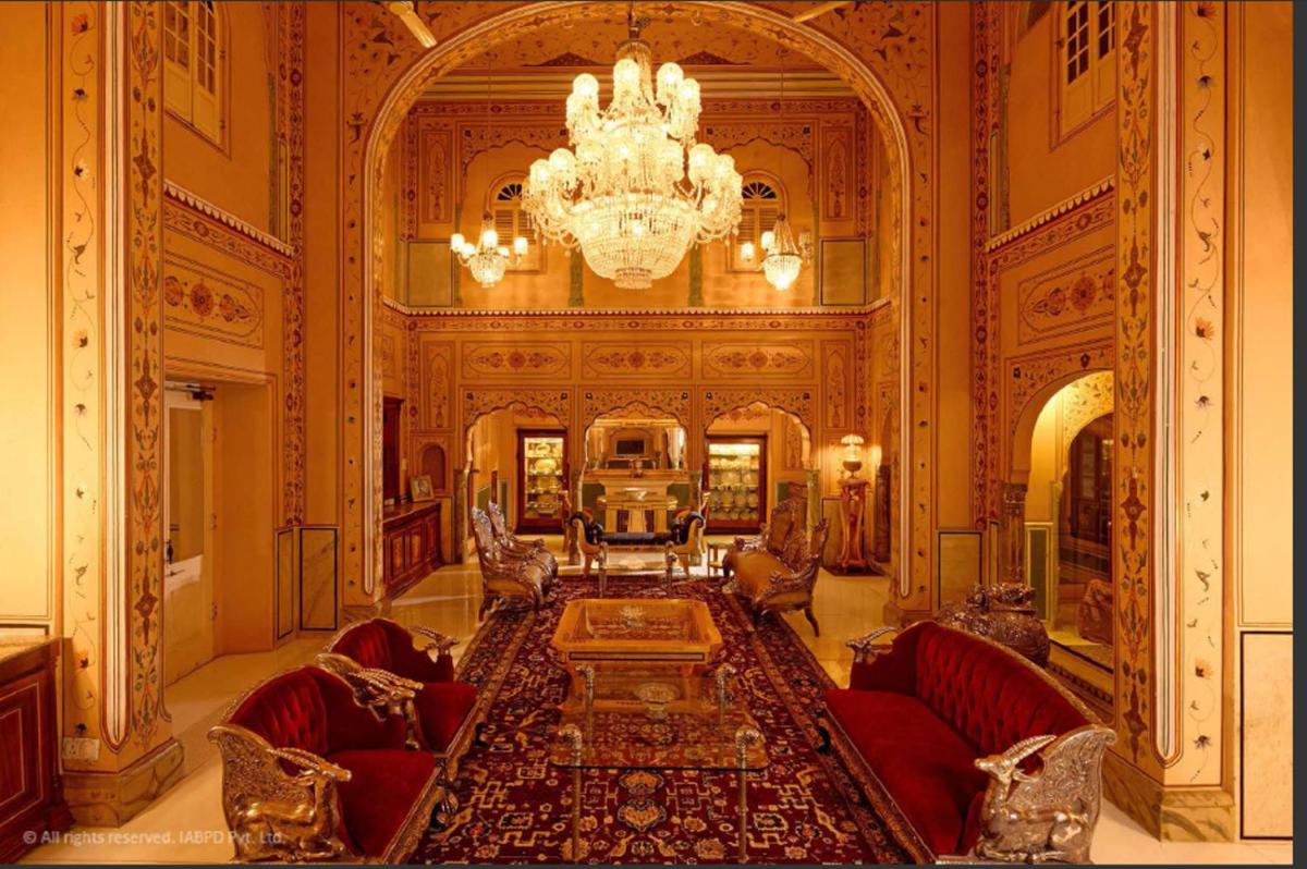 a large living room with a chandelier and red furniture at The Raj Palace (Small Luxury Hotels of the World) in Jaipur