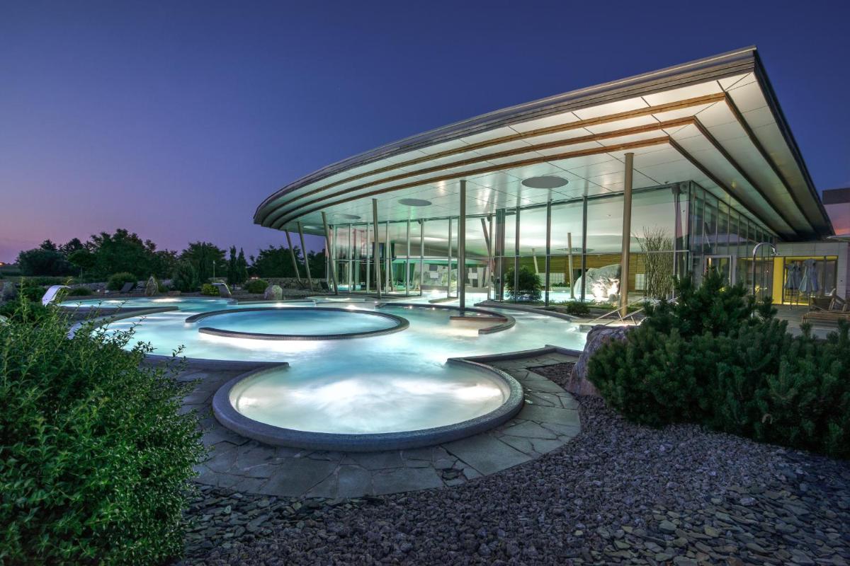 un bâtiment avec trois piscines devant dans l'établissement Hôtel Barrière Ribeauvillé, à Ribeauvillé