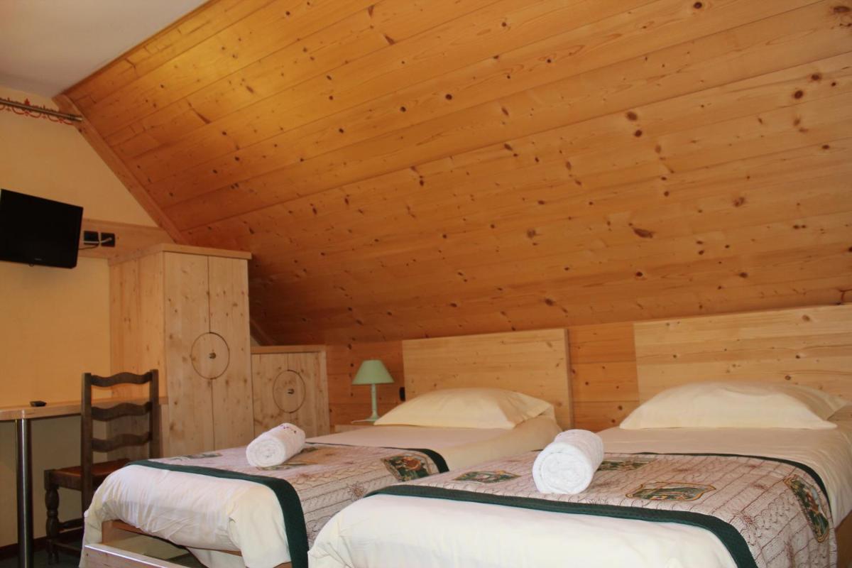 deux lits dans une chambre avec un plafond en bois dans l'établissement La Neyrette, à Saint-Disdier