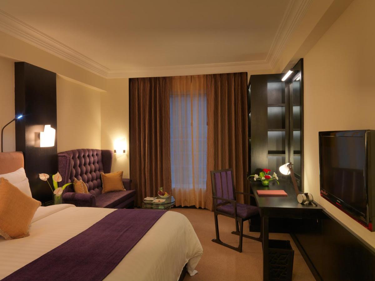 a hotel room with a bed and a desk and a tv at Sterlings Mac Hotel in Bengaluru