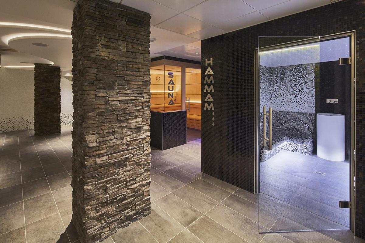un hall avec un pilier en briques et une porte dans l'établissement Kyriad Prestige Lyon Est - Saint Priest Eurexpo Hotel and SPA, à Saint-Priest