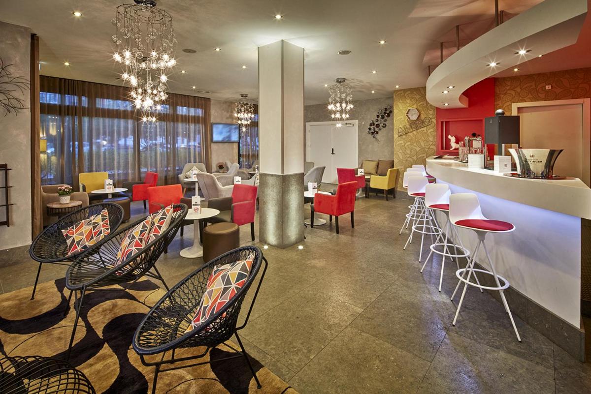 un restaurant avec des chaises et des tables et un bar dans l'établissement Kyriad Prestige Lyon Est - Saint Priest Eurexpo Hotel and SPA, à Saint-Priest