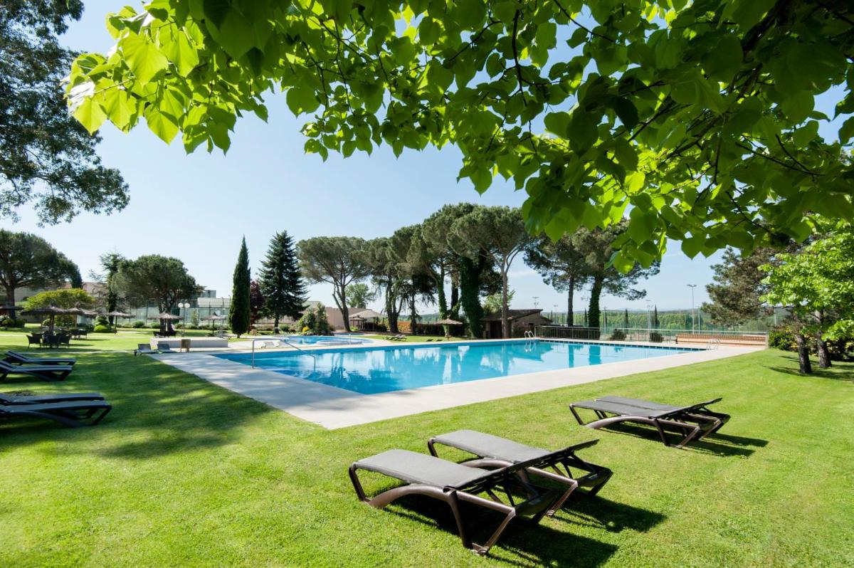 una piscina con 2 mesas de picnic en el césped en Hotel Mas Solà, en Santa Coloma de Farners 76 fotos más