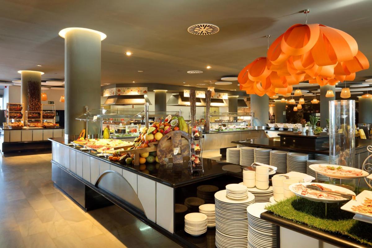 una línea de buffet en un restaurante con platos y comida en Grand Palladium White Island Resort & Spa - All Inclusive, en Playa d'en Bossa