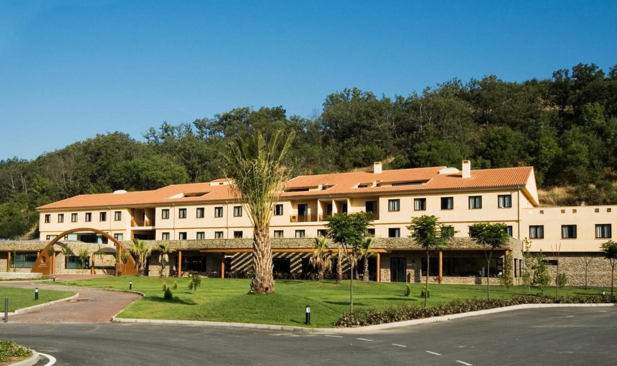un gran edificio blanco con árboles frente a una calle en Hotel Balneario Valle del Jerte, en Valdastillas